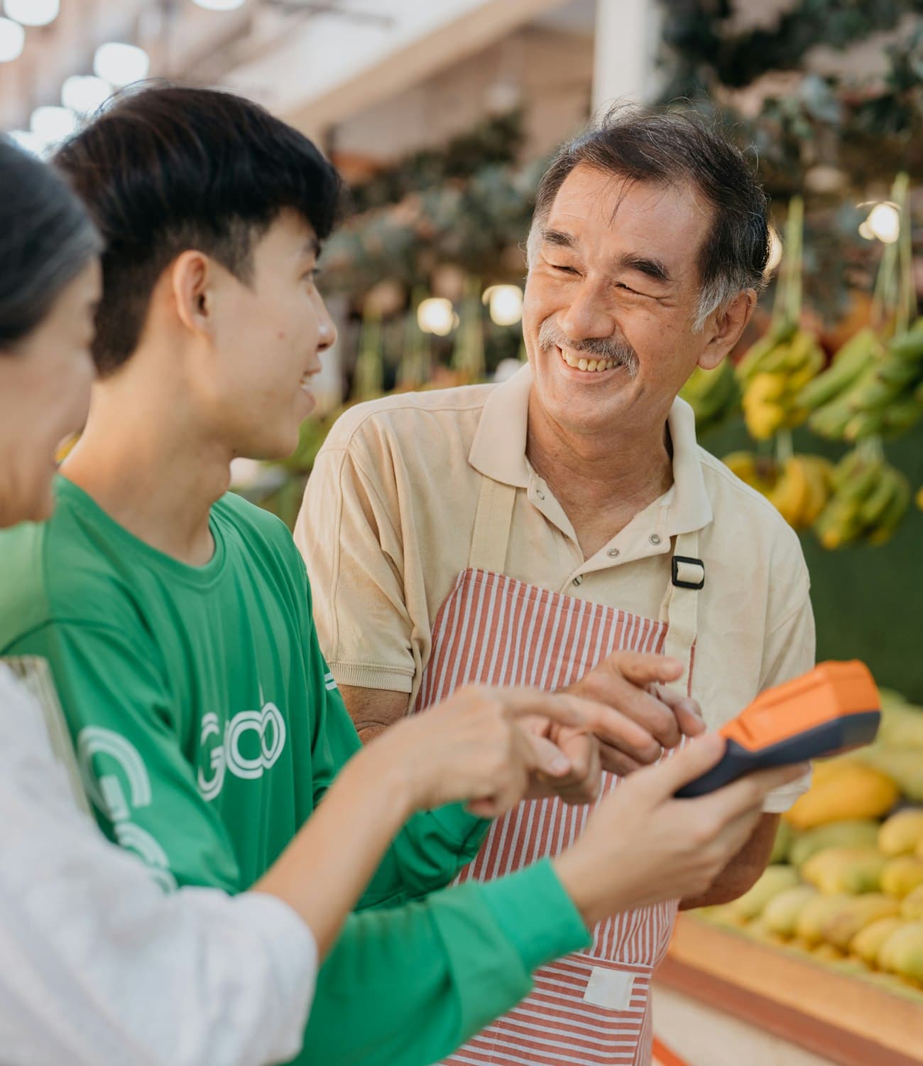 A shopkeeper and a customer completing a payment on a handheld terminal at a market stall