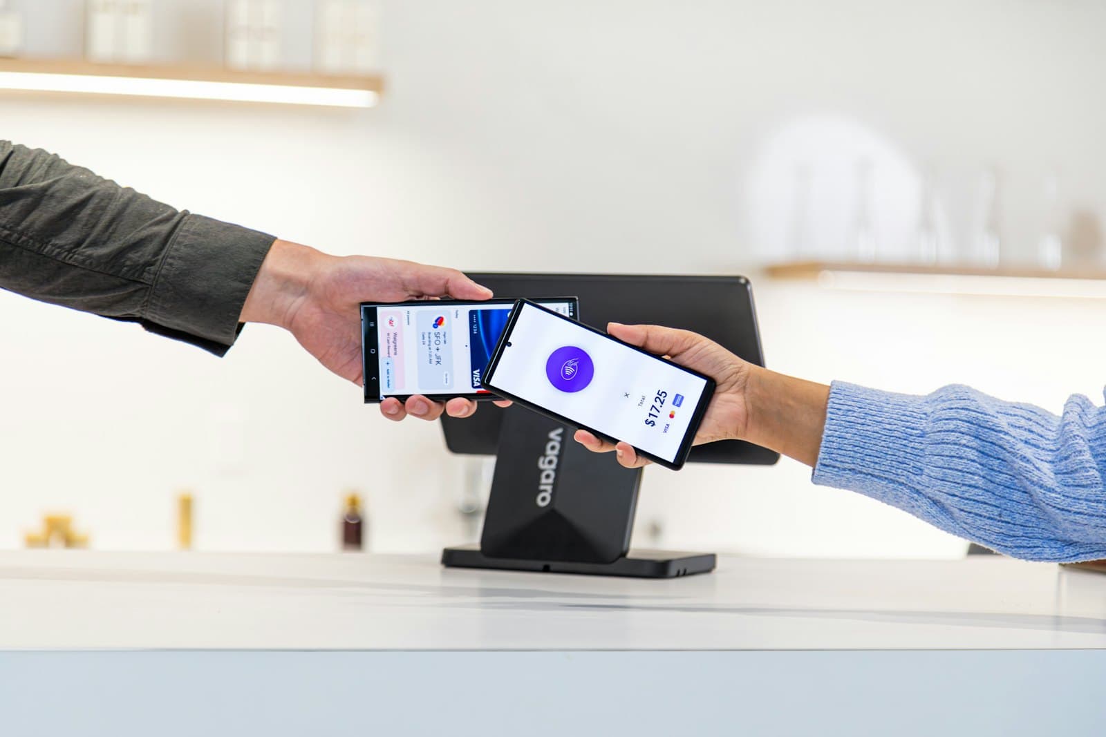 A customer and a shopkeeper completing a payment by phone at a counter